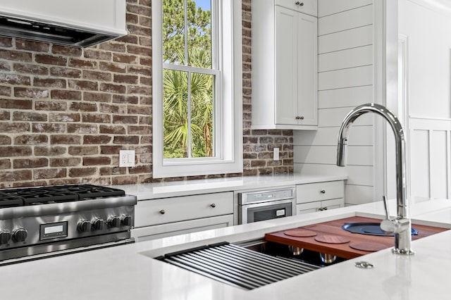 kitchen featuring stainless steel oven, cooktop, extractor fan, and white cabinets