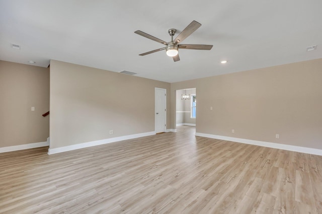 empty room featuring light hardwood / wood-style floors and ceiling fan with notable chandelier