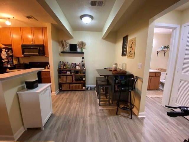 kitchen with light wood finished floors, baseboards, visible vents, and black microwave