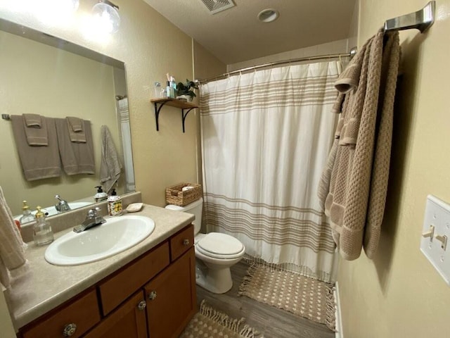 full bathroom featuring visible vents, toilet, wood finished floors, a shower with shower curtain, and vanity
