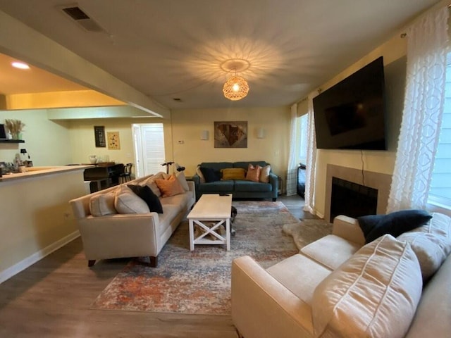 living room featuring a fireplace, plenty of natural light, wood finished floors, and visible vents