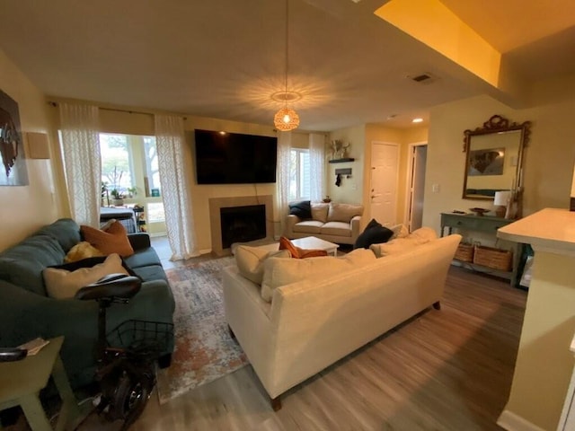 living room with a fireplace, wood finished floors, visible vents, and a healthy amount of sunlight