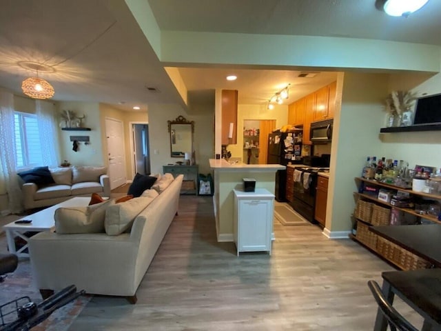 living area with visible vents, light wood-style flooring, and baseboards
