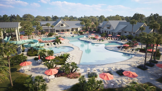 community pool featuring a water slide, a patio, and view of wooded area