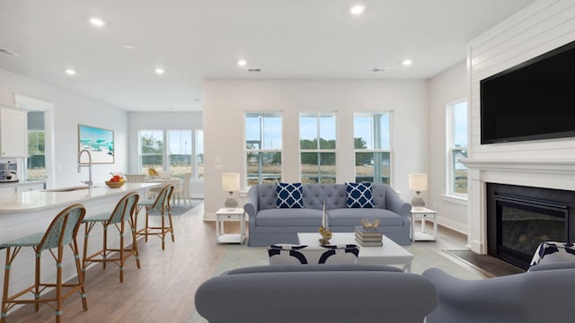 living area with recessed lighting, light wood-style flooring, a fireplace, and baseboards