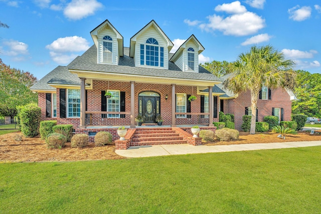 cape cod home with covered porch and a front lawn