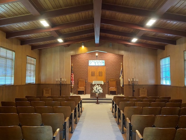 home theater room with lofted ceiling with beams, wood walls, carpet flooring, and a healthy amount of sunlight