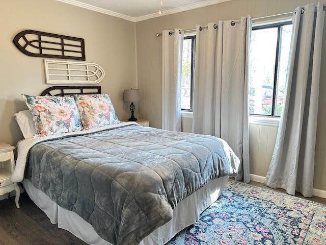 bedroom featuring ornamental molding, multiple windows, wood finished floors, and baseboards