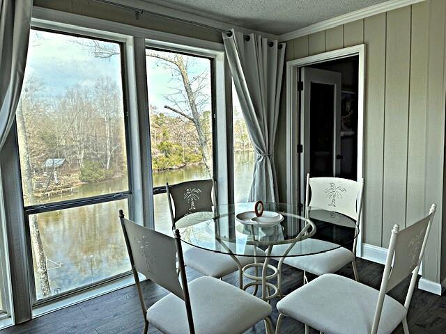 dining space featuring dark wood-style floors, ornamental molding, a textured ceiling, wooden walls, and baseboards
