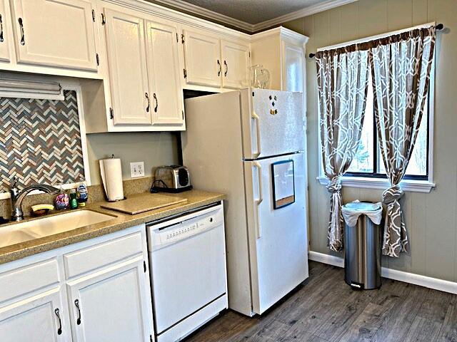 kitchen with white appliances, white cabinets, dark wood-style floors, ornamental molding, and a sink