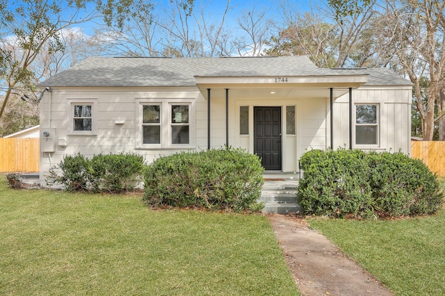 bungalow with a front lawn, roof with shingles, and fence