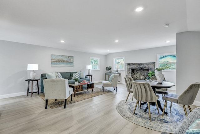living area with baseboards, light wood-style floors, a fireplace, and recessed lighting
