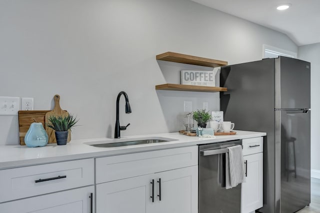 kitchen with white cabinets, light countertops, a sink, open shelves, and freestanding refrigerator