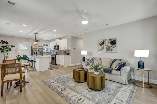 living area with light wood-style flooring, visible vents, and baseboards