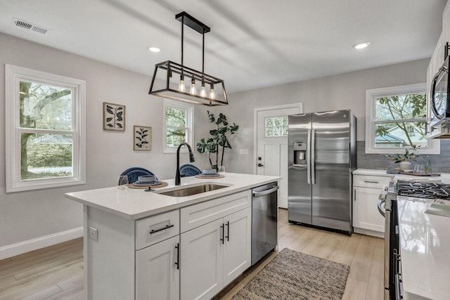 kitchen with light countertops, a sink, backsplash, appliances with stainless steel finishes, and visible vents