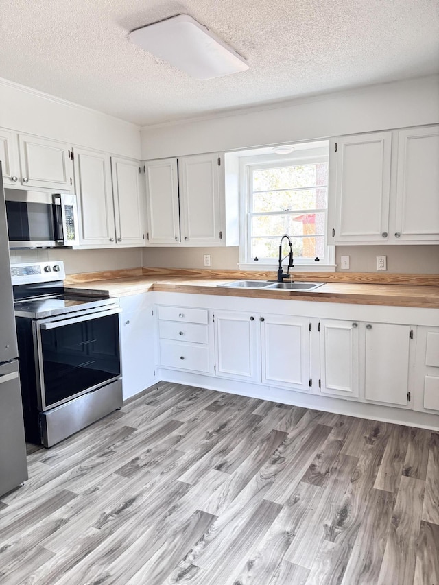 114 Madison St, Walterboro, SC 29488 - kitchen featuring stainless steel appliances, a textured ceiling, white cabinets, and light wood-style floors