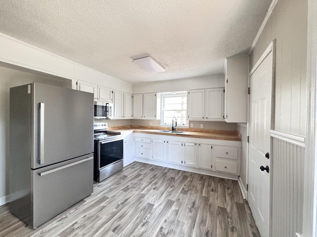 114 Madison St, Walterboro, SC 29488 - kitchen featuring stainless steel appliances, a textured ceiling, light wood-type flooring, and white cabinets