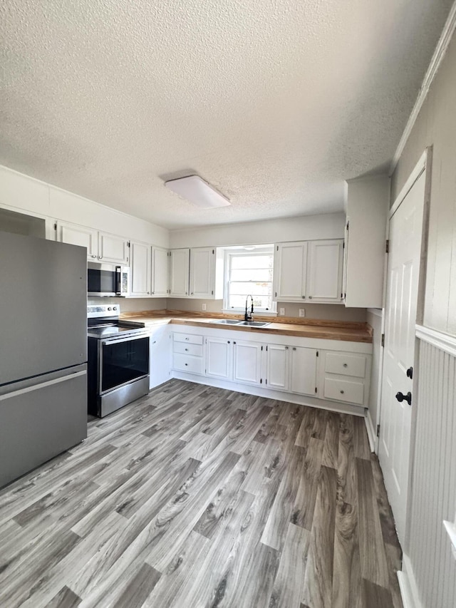 114 Madison St, Walterboro, SC 29488 - kitchen featuring stainless steel appliances, a textured ceiling, light wood-style flooring, white cabinets, and wood counters