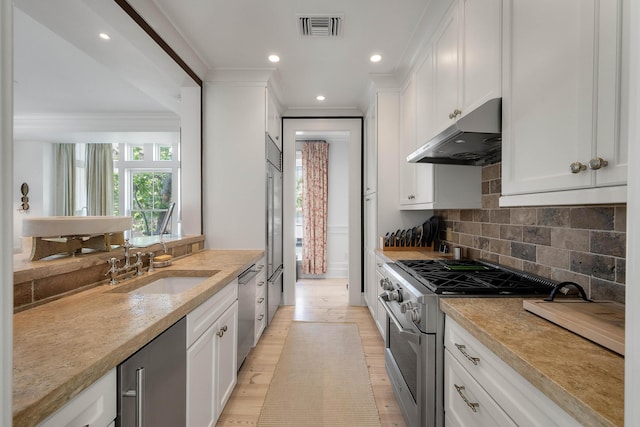 32 Prioleau St Unit J, Charleston, SC 29401 - kitchen with high end appliances, under cabinet range hood, ornamental molding, white cabinetry, and recessed lighting