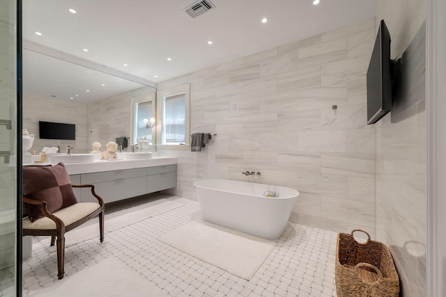 32 Prioleau St Unit J, Charleston, SC 29401 - bathroom with double vanity, a soaking tub, tile walls, and recessed lighting