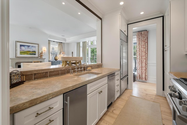 32 Prioleau St Unit J, Charleston, SC 29401 - kitchen with high quality appliances, white cabinetry, light wood-style floors, recessed lighting, and light stone counters