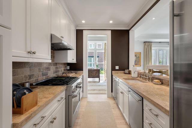 32 Prioleau St Unit J, Charleston, SC 29401 - kitchen with appliances with stainless steel finishes, under cabinet range hood, light countertops, crown molding, and recessed lighting
