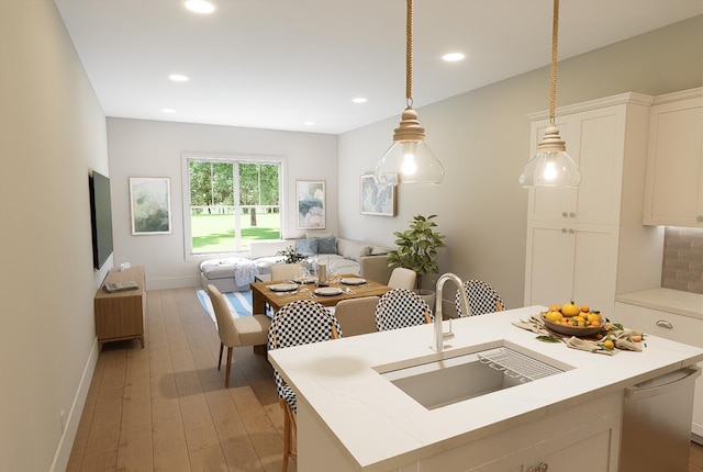 kitchen featuring white cabinets, light wood-style floors, a sink, and baseboards