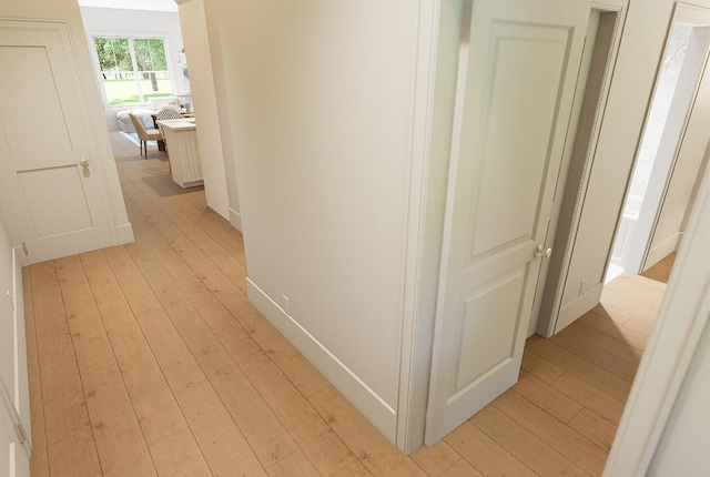 hall featuring baseboards and light wood finished floors