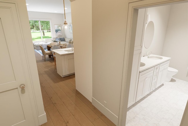 corridor with recessed lighting, light wood-style floors, and a sink