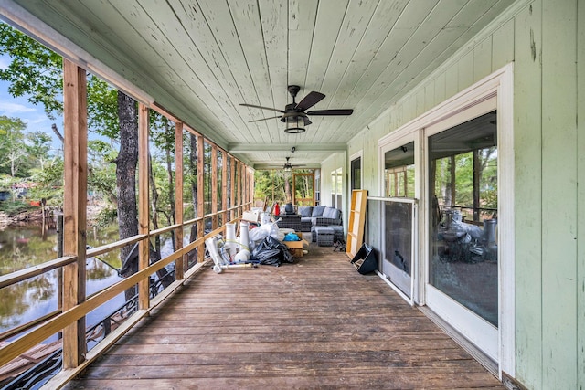 wooden terrace with a water view and ceiling fan