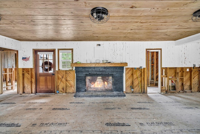 unfurnished living room featuring wooden ceiling, a fireplace, and wooden walls