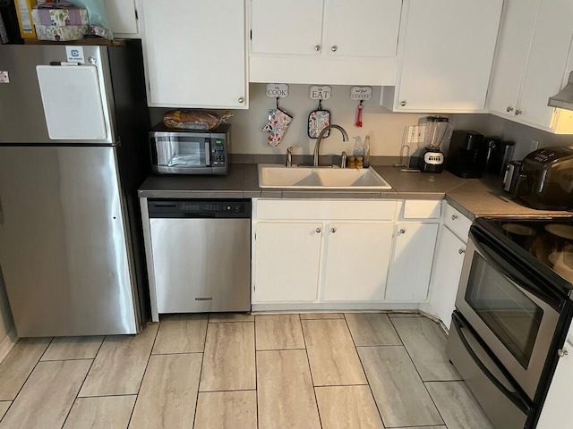 kitchen with appliances with stainless steel finishes, a sink, and white cabinetry