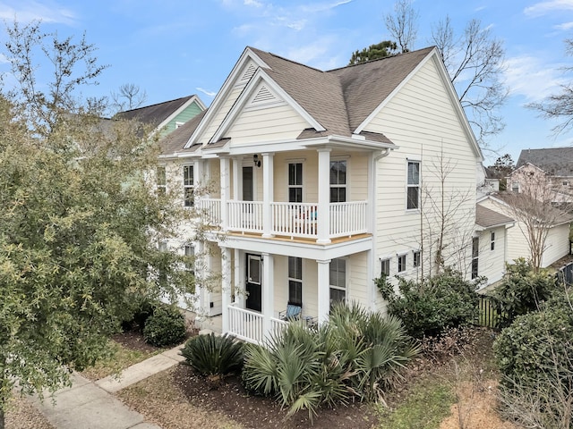 greek revival house with a balcony, covered porch, and roof with shingles