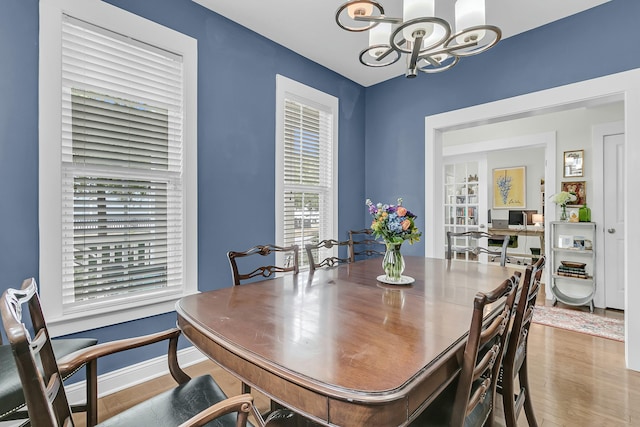 dining room with a notable chandelier, baseboards, and wood finished floors