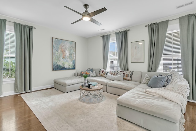 living room with a healthy amount of sunlight, baseboards, visible vents, and wood finished floors