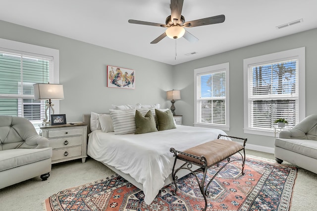 bedroom featuring light carpet, ceiling fan, visible vents, and baseboards