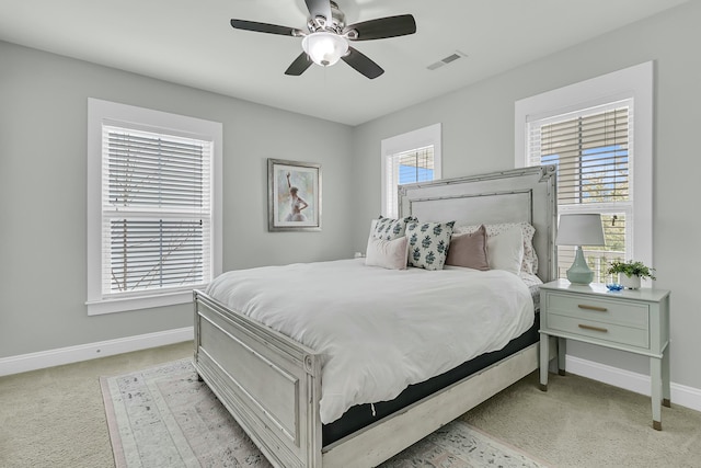 bedroom with baseboards, a ceiling fan, visible vents, and light colored carpet