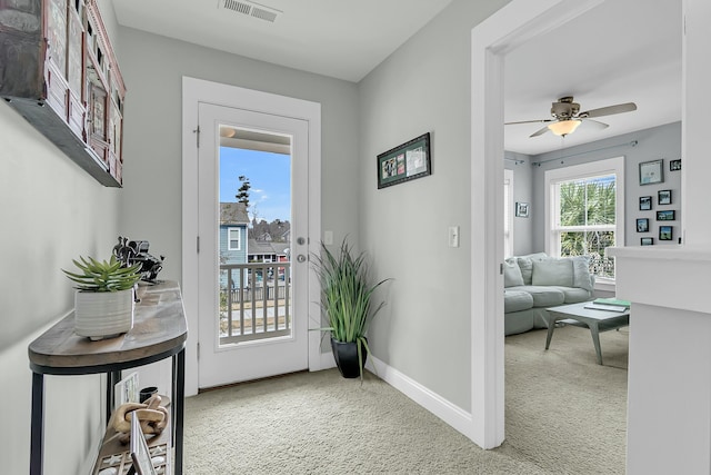 doorway featuring ceiling fan, carpet floors, visible vents, and baseboards