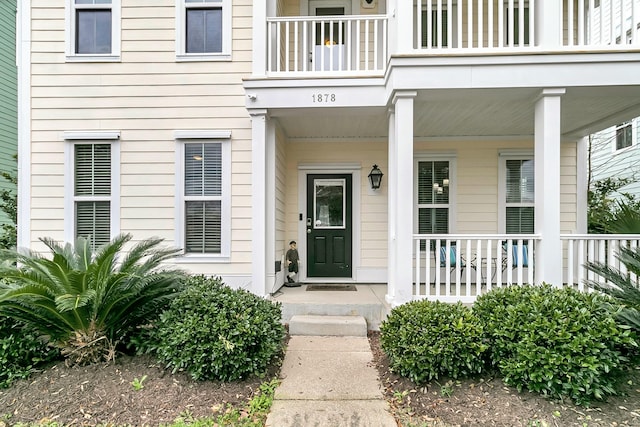 view of exterior entry featuring a porch and a balcony