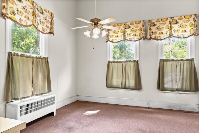 empty room featuring radiator, plenty of natural light, carpet, and ceiling fan