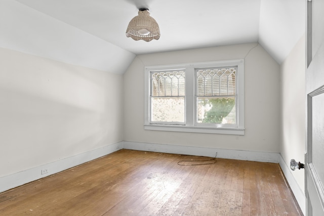 additional living space featuring vaulted ceiling, wood-type flooring, and baseboards