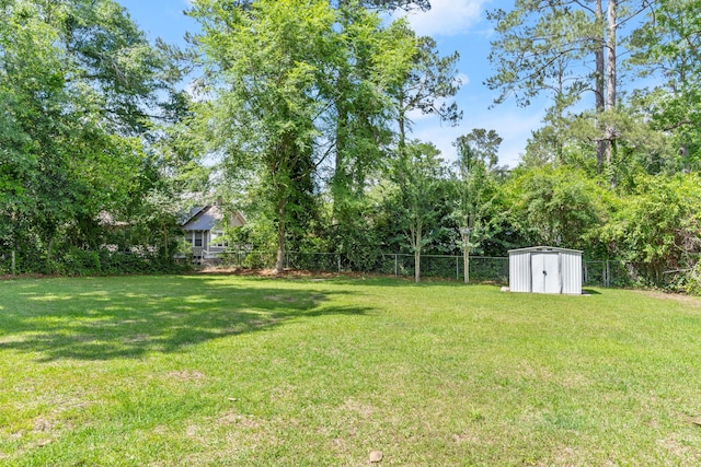 view of yard with a storage shed, an outdoor structure, and view of wooded area