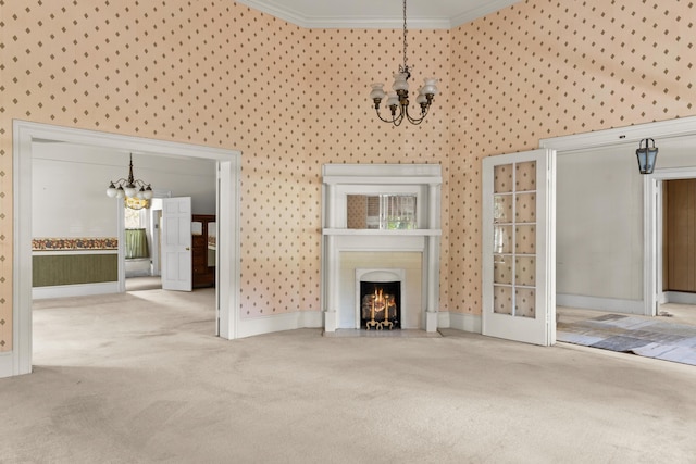 unfurnished living room with a chandelier, carpet floors, crown molding, wallpapered walls, and a fireplace with flush hearth