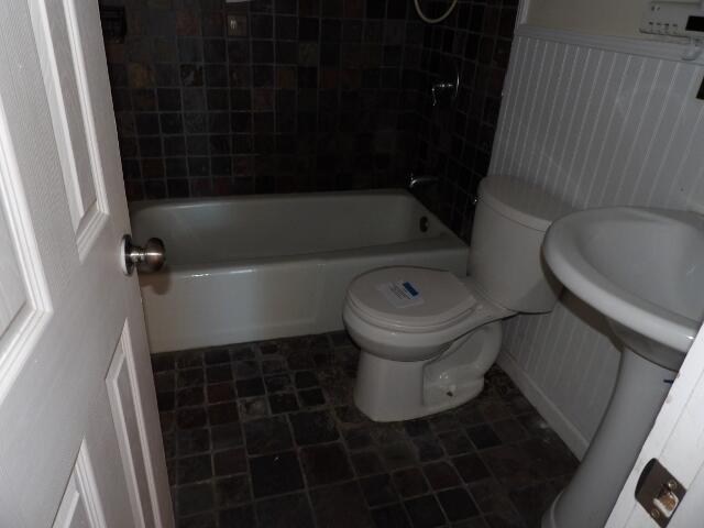 bathroom featuring toilet and tiled shower / bath combo