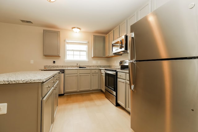 8285 Little Sydneys Way N, Charleston, SC 29406 - kitchen with appliances with stainless steel finishes, light stone counters, gray cabinetry, and light wood-style floors
