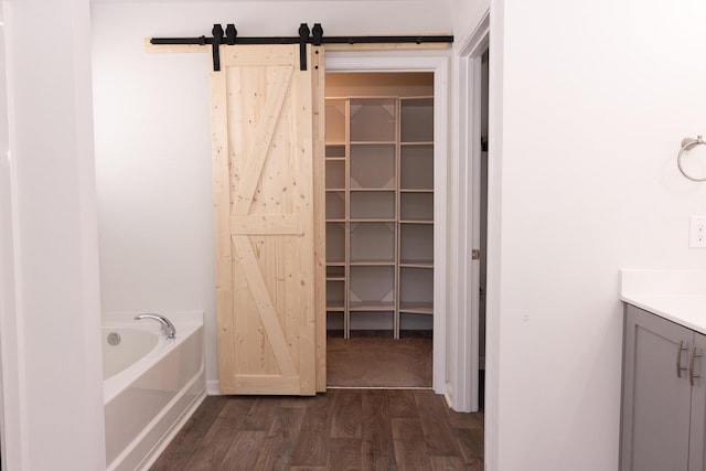 bathroom with wood finished floors, a bath, vanity, and baseboards