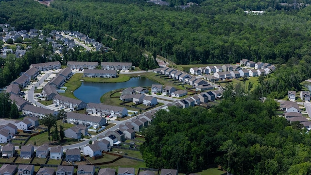 view of property location featuring a forest, nearby suburban area, and a nearby body of water