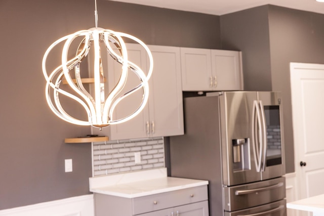 kitchen featuring stainless steel refrigerator with ice dispenser, tasteful backsplash, a chandelier, and light countertops