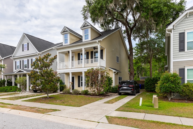 view of front facade featuring a balcony, covered porch, and a front yard