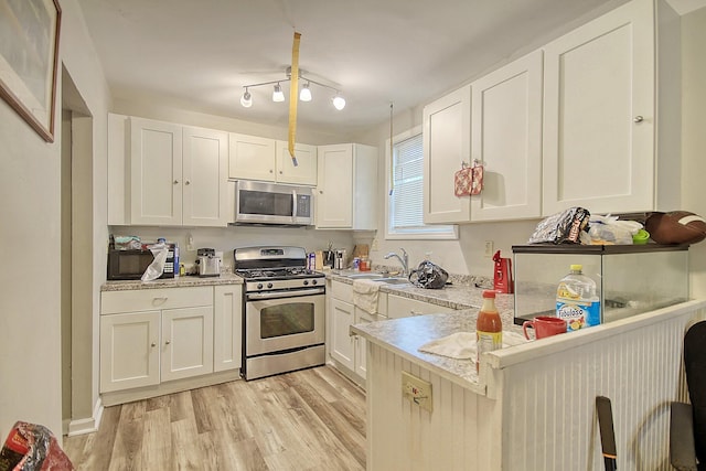 kitchen featuring white cabinetry, sink, stainless steel appliances, kitchen peninsula, and light hardwood / wood-style floors